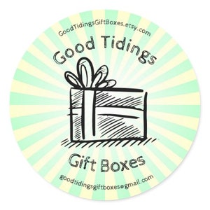May include: A round sticker with a light green and white striped background. The sticker features a hand-drawn illustration of a gift box with a bow. The words "Good Tidings" and "Gift Boxes" are written in a handwritten font.
