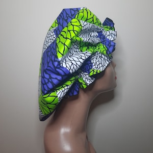 May include: A green, white, and purple patterned satin shower cap with a ruffled edge.