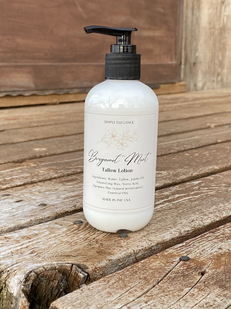 May include: A white bottle of Bergamot Mint Tallow Lotion with a black pump top. The label reads "Simple Elegance" and lists the ingredients: Water, Tallow, Jojoba Oil, Emulsifying Wax, Steric Acid, Optiphen Plus (natural preservative), Essential Oils. The bottle is made in the USA.