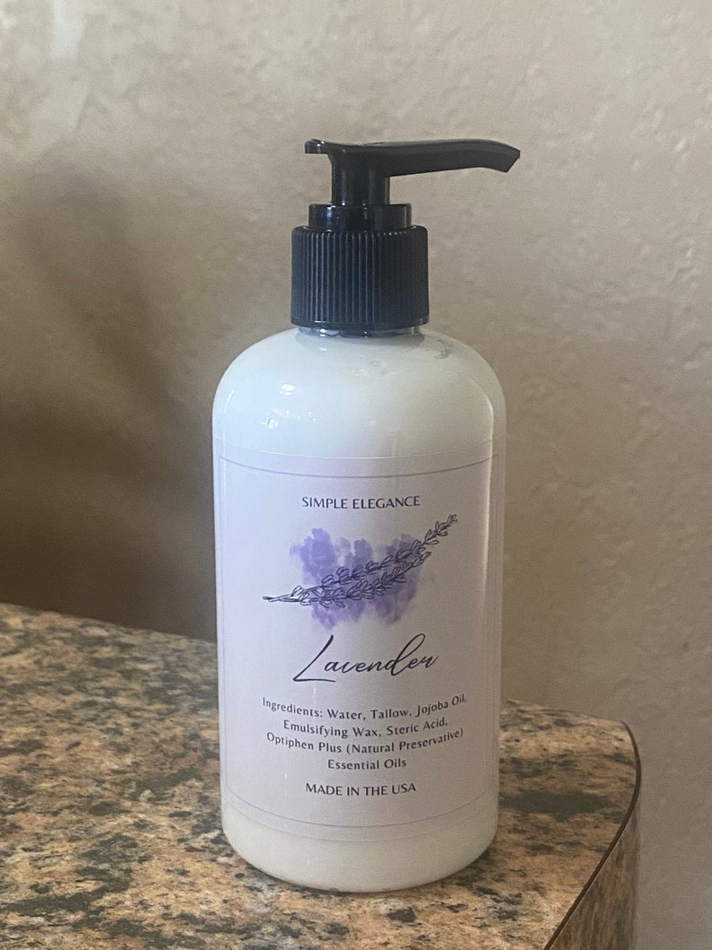 May include: A white bottle with a black pump top and a label that reads "Simple Elegance Lavender". The label also lists the ingredients: water, tallow, jojoba oil, emulsifying wax, stearic acid, optiphen plus (natural preservative), and essential oils. The bottle is made in the USA.