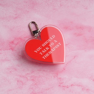 May include: Red heart-shaped keychain with the text "YOU SHOULD TALK TO A THERAPIST" in white lettering.