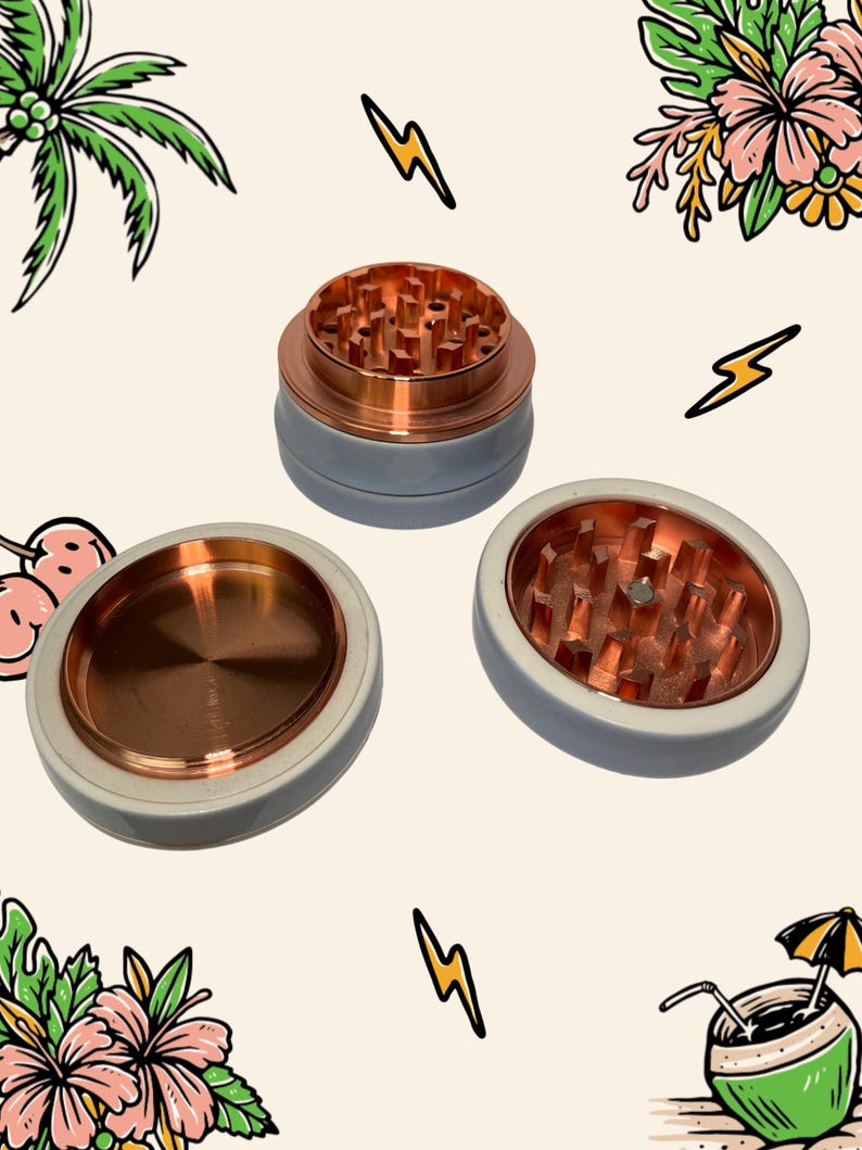 May include: A three-piece herb grinder with a matte light grey exterior and a metallic copper interior. The grinder features sharp, pyramid-shaped teeth for processing herbs, with one section showing a flat, circular copper base.