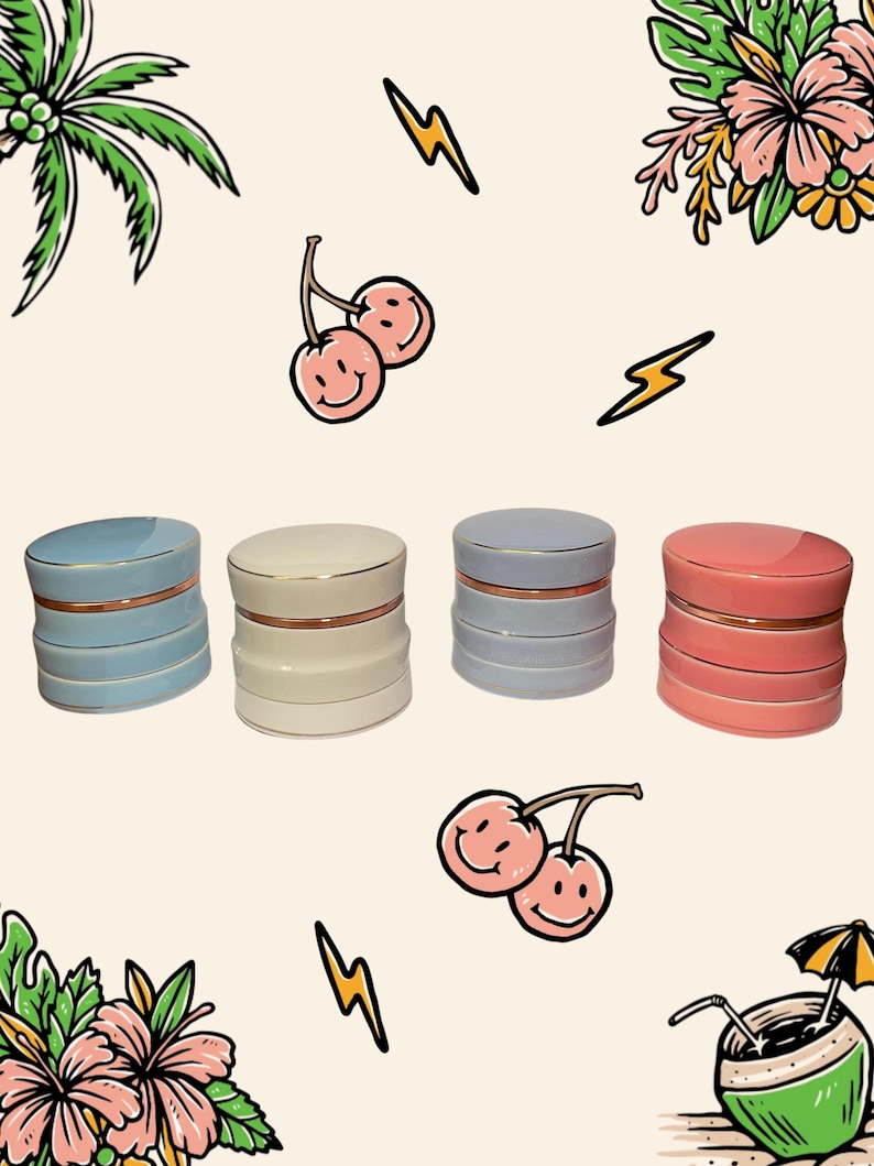 May include: Four cylindrical ceramic containers with lids, each featuring a metallic gold rim. The containers are coloured light blue, cream, light grey, and coral pink. The background is decorated with illustrations of palm leaves, cherries, lightning bolts, and a coconut drink.