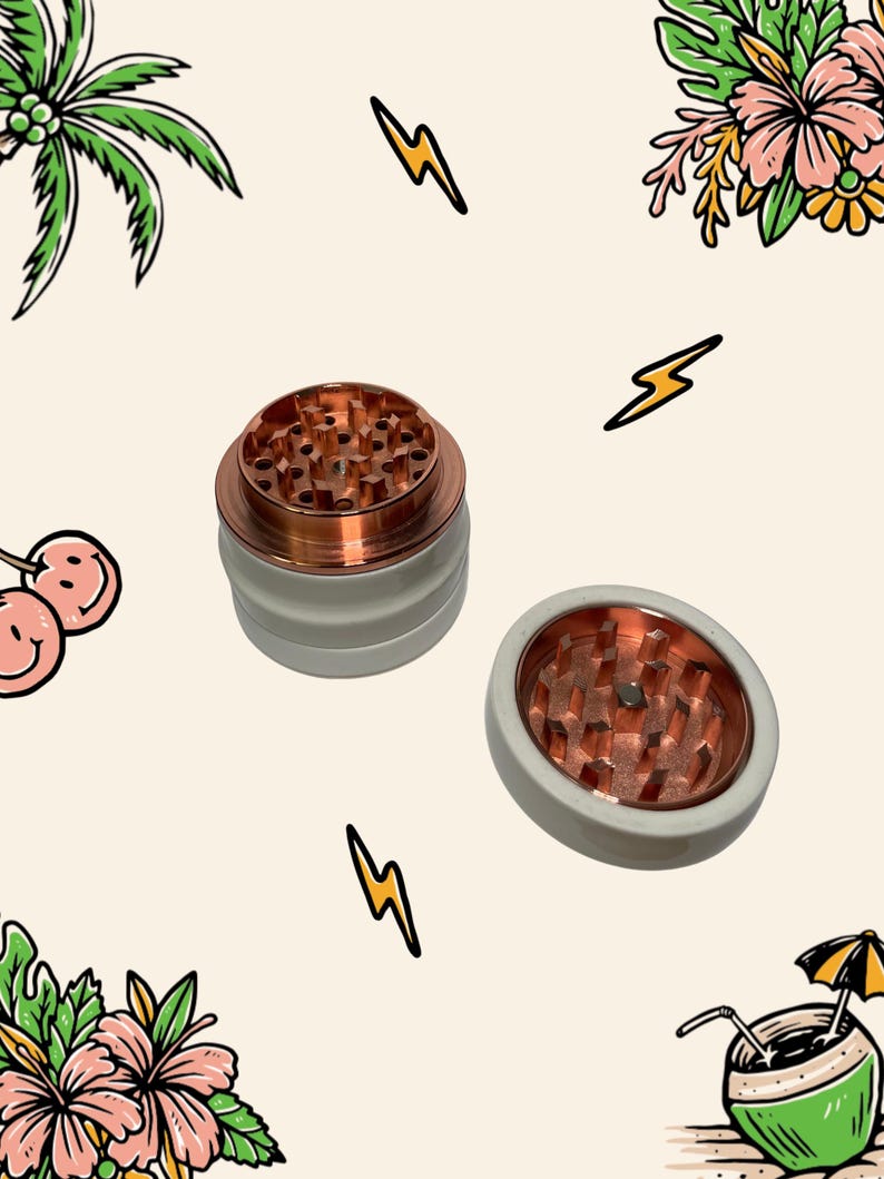 May include: A two-piece herb grinder featuring a matte white exterior and a metallic copper interior. The top section is shown upright, while the bottom section is placed flat, both revealing sharp, diamond-shaped copper teeth for grinding.