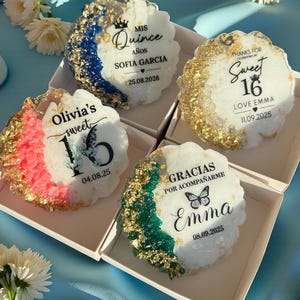 Peut inclure: Quatre dessous de verre décoratifs en résine avec des accents de feuilles d'or et du texte. Chaque dessous de verre a un design unique, avec des inscriptions telles que "Mis Quince", "Sweet 16" et "Gracias por acompañarme".