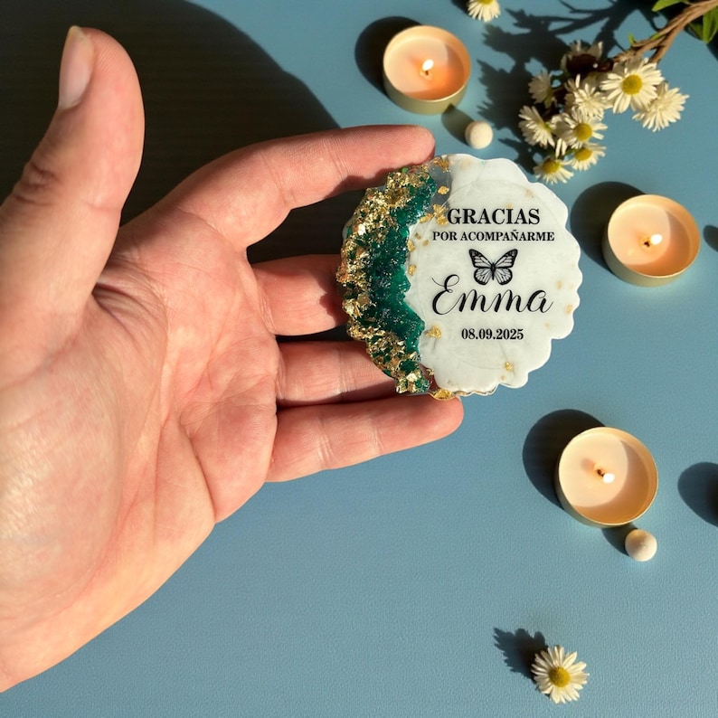 May include: A decorative, irregular-shaped coaster with a white base, green and gold accents, and the name "Emma" with a butterfly illustration. The coaster also includes the date 08.09.2025.