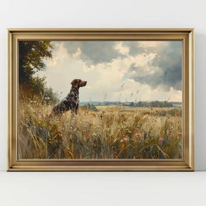 May include: A framed print depicting a dog in a field. The dog, with brown and black markings, is positioned in tall grass and wildflowers. The background shows a cloudy sky and a distant landscape. The frame is gold-coloured.