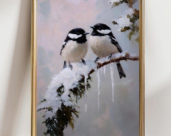 May include: A framed painting depicts two small birds with black and white plumage perched on a snow-covered branch. The artwork features a soft, pastel color palette with a gold-colored frame, evoking a winter scene.