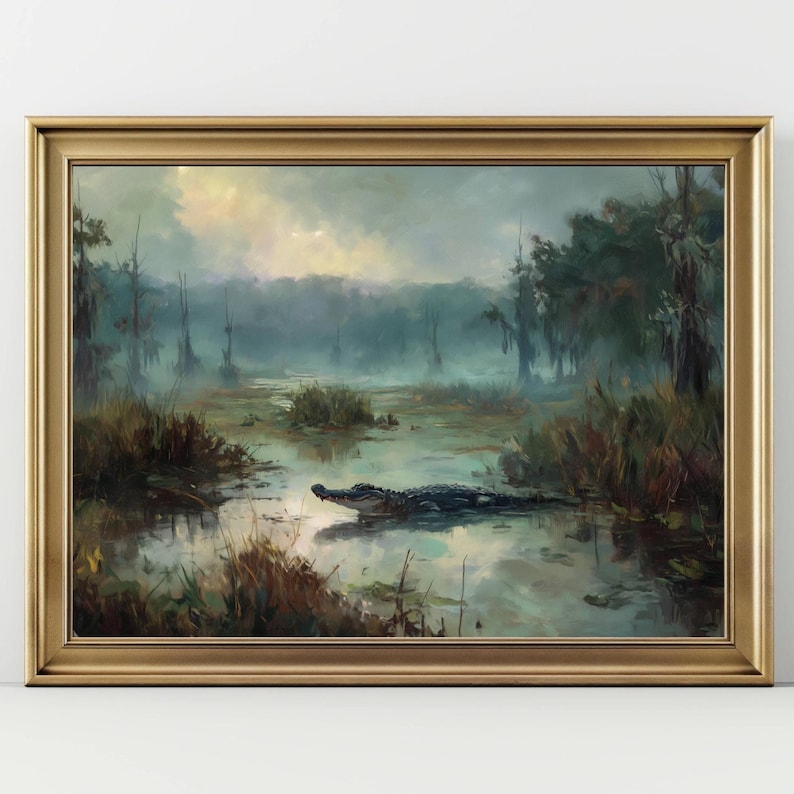 May include: A framed landscape painting depicts a swamp scene with an alligator in the water. The artwork features a gold frame and a misty, atmospheric setting with trees and vegetation. The color palette includes greens, blues, and browns.