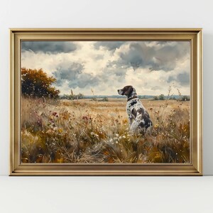 May include: A framed painting depicts a dog with brown and white spots sitting in a field of tall grass and wildflowers. The dog is looking towards the horizon under a cloudy sky. The painting is in a gold frame.