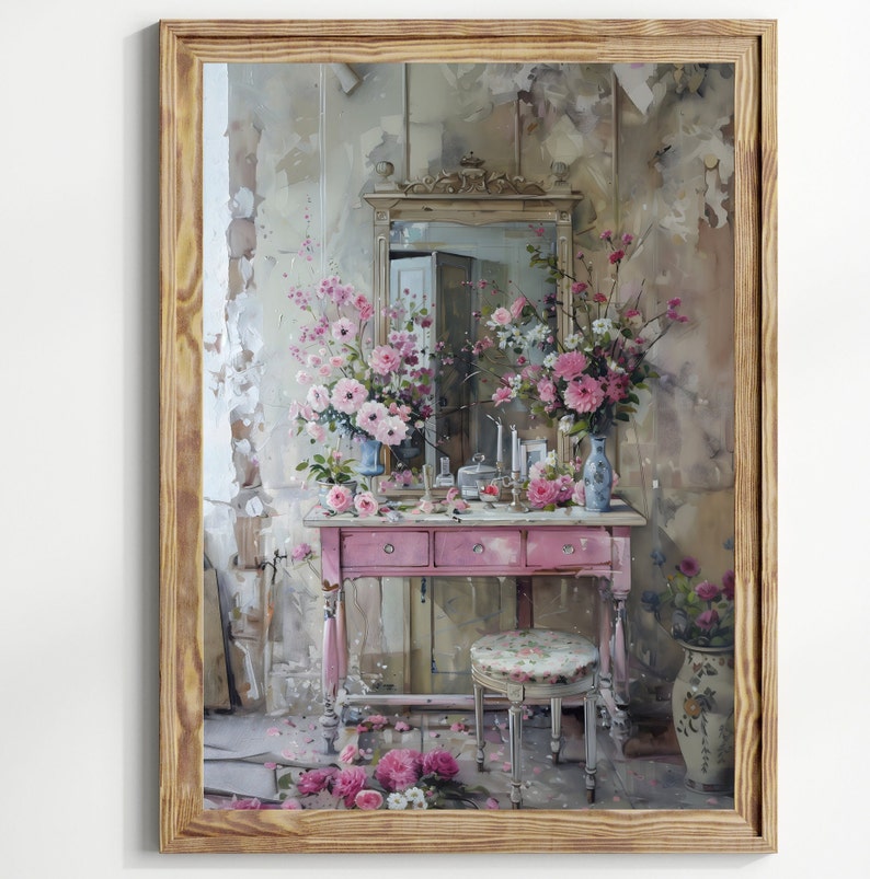 K&ouml;nnte beinhalten: Ein Vintage-Schminktisch-Set mit rosafarbener Lackierung. Der Schminktisch hat drei Schubladen und einen Spiegel mit einem verzierten Rahmen. Der Schminktisch ist mit rosa Blumen und einer Vase dekoriert. Der Schminktisch steht vor einem Hintergrund einer hellgrauen Wand mit einem abgenutzten Look.
