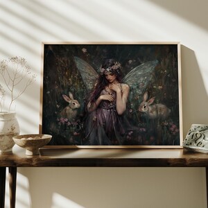 May include: A painting of a fairy with wings and a flower crown, standing in a forest with two rabbits. The fairy is wearing a purple dress and has long brown hair. The background is a dark green forest with flowers.