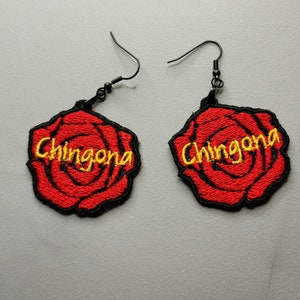 May include: A pair of earrings featuring red embroidered roses with the word "Chingona" in yellow thread.