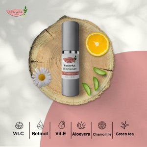 Pode incluir: Um frasco prateado de soro facial potente CosmoCan com um r&oacute;tulo branco. O frasco est&aacute; sobre uma superf&iacute;cie de madeira com uma fatia de laranja, folhas de aloe vera e uma margarida. O r&oacute;tulo lista os ingredientes: vitamina C, retinol, vitamina E, aloe vera, camomila e ch&aacute; verde.