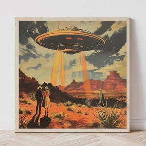 May include: A square wall art print featuring a desert landscape with red rock formations and cacti. Two figures stand in the foreground looking up at a large, dark, disc-shaped UFO hovering in the sky, emitting bright orange beams of light downward.