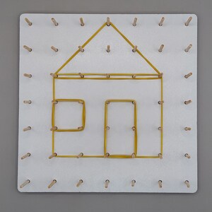 Könnte beinhalten: Eine weiße Stecktafel mit Holzstiften, die in einem Raster angeordnet sind. Ein gelbes Gummiband bildet die Form eines Hauses, einschließlich Dach, Tür und Fenster. Dieses Lernspielzeug ist für das Erlernen von Formen und Feinmotorik konzipiert.