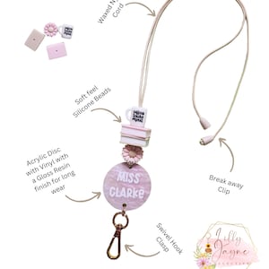 Pu&ograve; includere: Lacci rosa e bianchi con un ciondolo a forma di tazza di caff&egrave;, un ciondolo a forma di fiore e un'etichetta rotonda con il nome "Miss Clarke". Il laccio ha una chiusura a gancio girevole e un clip di sicurezza.