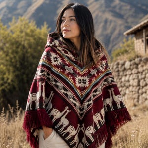 Può includere: Un poncho con cappuccio con un motivo geometrico e di lama nei colori bordeaux, crema e marrone. Il poncho ha un orlo con frange e viene indossato all'aperto. Il design presenta motivi ripetuti e uno scollo a V.