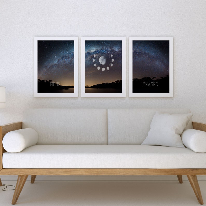 May include: Three framed art prints depicting the night sky and moon phases. The center print shows the moon's phases in a circular arrangement. The prints are in white frames and hang above a light-colored sofa. The word "MOON" is printed on the left print and "PHASES" on the right.