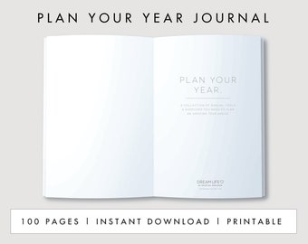 May include: A white journal with the text "PLAN YOUR YEAR" on the cover. The journal is open to a page with the text "PLAN YOUR YEAR. A COLLECTION OF ANNUAL TOOLS & EXERCISES YOU NEED TO PLAN AN AMAZING YEAR AHEAD. DREAM LIFE."