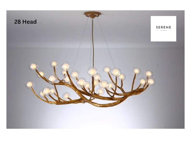 May include: A gold-toned, 28-head chandelier with a unique branch-like design and clear glass globes. The chandelier is suspended from the ceiling by a chain.