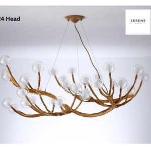 May include: A 24-head chandelier with a unique branch-like design and clear glass globes. The chandelier is made of wood and has a gold finish.