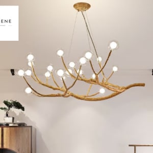 May include: A gold-toned chandelier with a unique branch-like design and clear glass globes. The chandelier is hanging from the ceiling in a room with white walls.