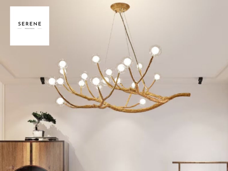 May include: A gold-toned chandelier with a unique branch-like design and clear glass globes. The chandelier is hanging from the ceiling in a room with white walls.