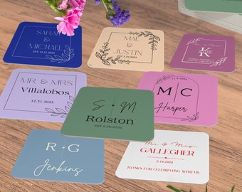 Puede incluir: Una colección de nueve posavasos cuadrados con diferentes diseños y colores. Cada posavasos presenta los nombres de una pareja, la fecha de su boda y sus iniciales. Los posavasos están hechos de un material grueso y duradero, perfectos para proteger las superficies de derrames y arañazos.