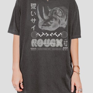 May include: A black oversized t-shirt with a graphic print of a rhinoceros, the word "ROUGH" in a stylized font, and Japanese text. The text "ESTABLISHED 2005 OKINAWA, JPN" is also printed on the shirt.