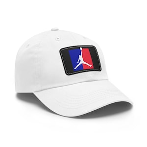 May include: White baseball cap with a black, blue and red patch featuring a silhouette of a basketball player dunking. The patch has a stitched border.