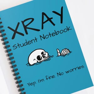 May include: A spiral-bound notebook with a bright blue cover. The cover features the word "XRAY" in large black letters, with "Student Notebook" below. A cartoon skull and hand are also on the cover, with the text "Yep. I'm fine. No worries."