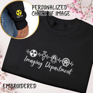 May include: Black sweatshirt with white embroidered text and graphics. The text reads "Imaging Department" with related medical symbols. A yellow and black radiation symbol is on the sleeve. The words "Personalized Choice of Image" and "Embroidered" are also visible.