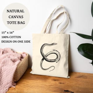 May include: A natural canvas tote bag, approximately 38cm x 41cm, featuring a black snake illustration and the text "Shed what no longer serves you." The bag is made of 100% cotton and has a design on one side.
