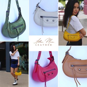 May include: A set of five leather handbags in different colors, including green, white, yellow, pink, and brown. The handbags have a curved shape and a single strap. The handbags are all made of leather and have a simple design.