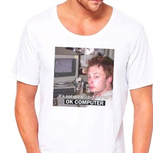 May include: White t-shirt with a photo of a man in front of a computer. The text on the shirt reads "It's not great... but it's an OK COMPUTER."