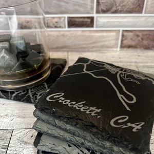 May include: Set of four black slate coasters with a map of Crockett, CA and the text "Crockett, CA" engraved on the top coaster.