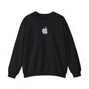 May include: Black crewneck sweatshirt featuring a light gray apple logo centered on the chest. The long-sleeved top is made of a soft material and is suitable for casual wear. The design is simple and minimalist.