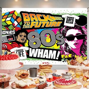May include: A colorful 80s themed party backdrop with the text "Back to the Future" and "Wham!"  The backdrop also features images of a Rubik's Cube, a video game controller, a cassette tape, a microphone, and a Pac-Man character.