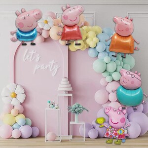May include: A party scene featuring Peppa Pig balloons and a pink backdrop. The display includes a pink arch, a cake, and the words "let's party". Pastel-coloured balloons and floral decorations create a celebratory atmosphere.