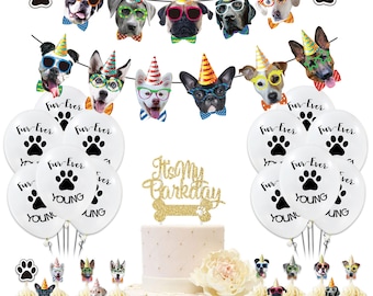 Puede incluir: Un pastel blanco con glaseado de brillo dorado y una decoración que dice "It's My Barkday". El pastel está rodeado de globos blancos con huellas de patas negras y las palabras "Fur-Ever" y "Young". También hay cupcakes con decoraciones de temática canina.