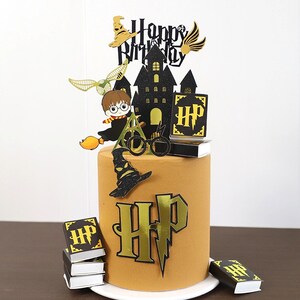 May include: A Harry Potter themed cake topper set featuring a black castle, a golden snitch, a black and gold 'Happy Birthday' banner, a black and gold 'HP' book, a black and gold 'HP' logo, a black and gold Sorting Hat, a black and gold pair of glasses, a black and gold broomstick, and a black and gold figure of Harry Potter.