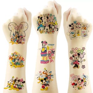 May include: A collection of temporary tattoos featuring colourful Disney character illustrations including Mickey Mouse, Minnie Mouse, Donald Duck, Daisy Duck, and Pluto. The designs include various scenes, floral arrangements, and the text SHOP TILL YOU DROP.