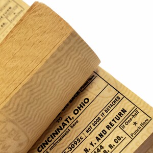 K&ouml;nnte beinhalten: Ein Stapel alter Papiertickets mit einem Zickzackmuster. Das oberste Ticket lautet "TO CINCINNATI, OHIO" und "NOT GOOD IF DETACHED". Das unterste Ticket lautet "N. Y. AND RETURN" und "B. R. CO."
