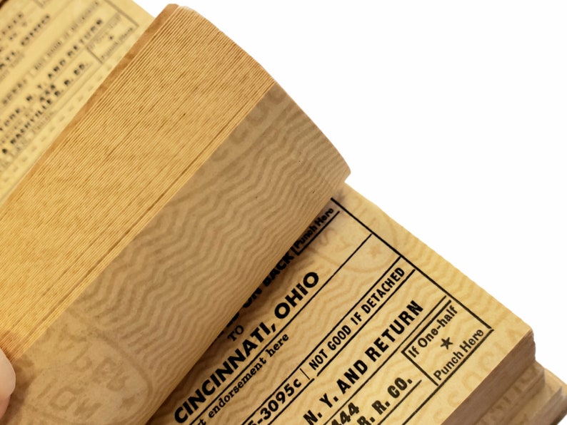 K&ouml;nnte beinhalten: Ein Stapel alter Papiertickets mit einem Zickzackmuster. Das oberste Ticket lautet "TO CINCINNATI, OHIO" und "NOT GOOD IF DETACHED". Das unterste Ticket lautet "N. Y. AND RETURN" und "B. R. CO."