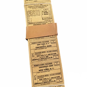 K&ouml;nnte beinhalten: Ein Stapel alter Zugtickets f&uuml;r Reisen zwischen New York, NY und Cincinnati, Ohio mit der Pennsylvania Railroad. Die Tickets sind datiert und haben eine G&uuml;ltigkeit von 30 Tagen oder 3 Monaten. Die Tickets sind braun und haben schwarzen Text.