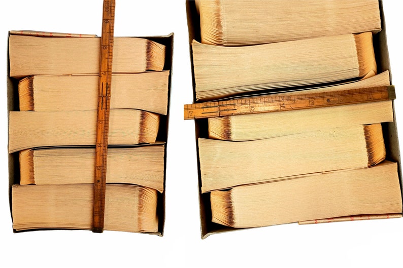 May include: Two stacks of old, yellowed books are bound together with wooden rulers. The stacks are in cardboard boxes. The books are about 12 inches tall.