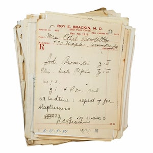 May include: A stack of old, yellowed papers with handwritten notes and a prescription for "Lod. Promise" with instructions to take "Clit lasts lepin 5/10" and "3 i 4 P.M. and at bedtime: repeat if for sleeplessness". The prescription is dated 11-8-41 and signed "R.E. Brackin, M.D."