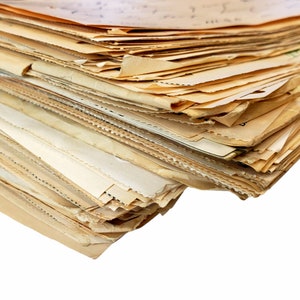 May include: A large stack of old, yellowed, and worn paper documents. The papers are stacked in a haphazard way, with some of the edges sticking out.