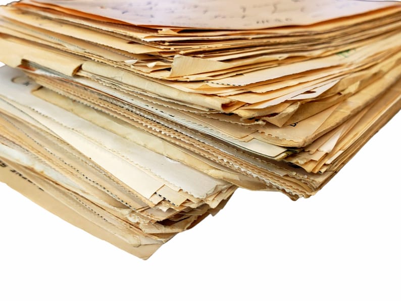 May include: A large stack of old, yellowed, and worn paper documents. The papers are stacked in a haphazard way, with some of the edges sticking out.